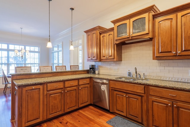 kitchen with kitchen peninsula, a notable chandelier, decorative light fixtures, stainless steel dishwasher, and sink