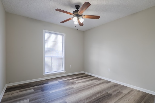 empty room with ceiling fan, light wood-type flooring, and a textured ceiling