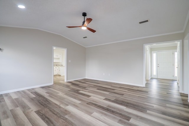 spare room featuring ceiling fan, vaulted ceiling, crown molding, and light hardwood / wood-style flooring