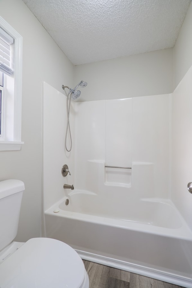 bathroom with shower / bath combination, a textured ceiling, hardwood / wood-style flooring, and toilet