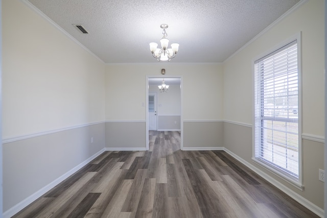 spare room with a chandelier, a textured ceiling, dark hardwood / wood-style flooring, and a wealth of natural light