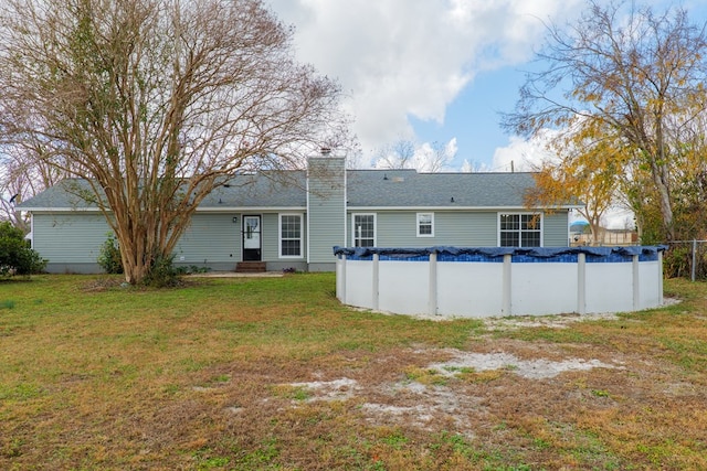 rear view of house featuring a yard and a covered pool