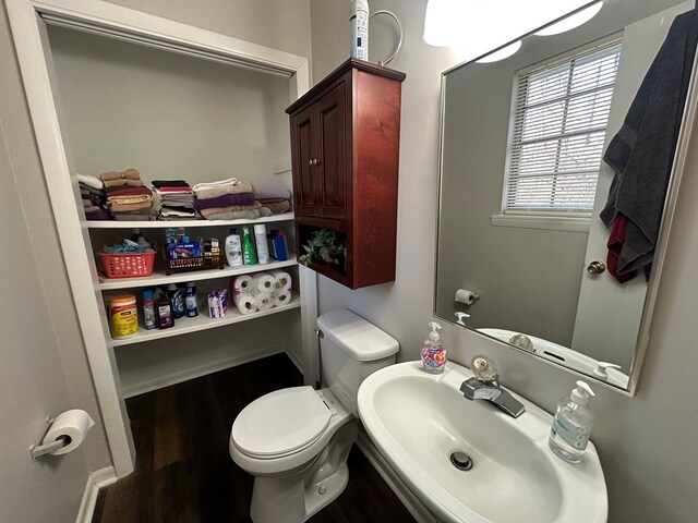 half bath featuring a sink, toilet, and wood finished floors