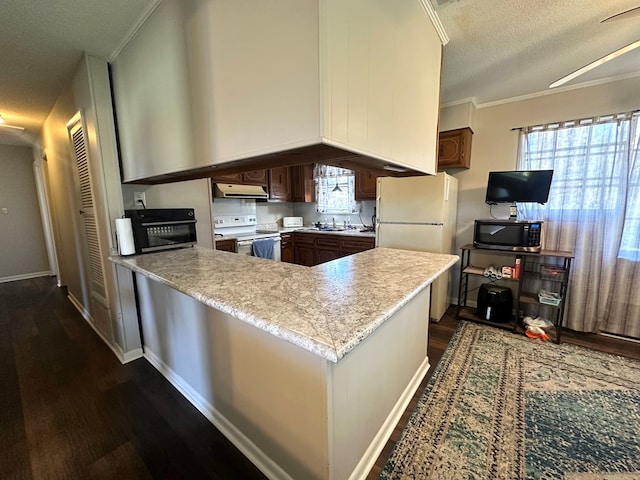 kitchen with light countertops, range hood, a peninsula, white appliances, and a sink