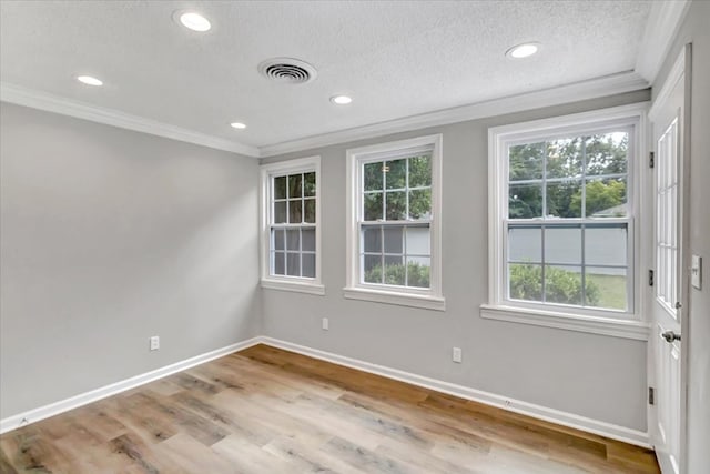 spare room featuring ornamental molding, a textured ceiling, and light hardwood / wood-style flooring