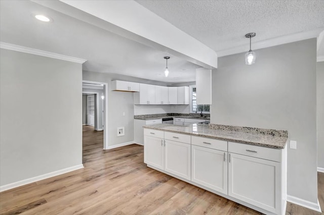 kitchen with light stone countertops, light wood-type flooring, a textured ceiling, decorative light fixtures, and white cabinetry