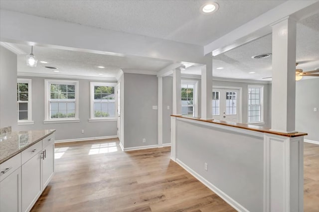 kitchen featuring light stone countertops, plenty of natural light, light wood-type flooring, and white cabinetry