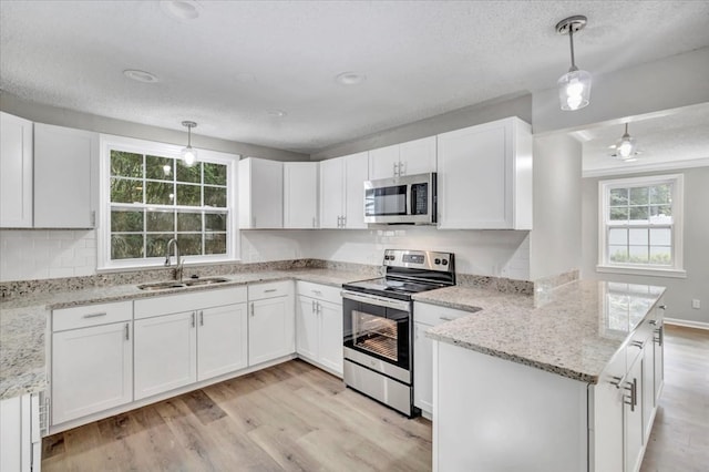 kitchen featuring white cabinetry, pendant lighting, stainless steel appliances, and sink