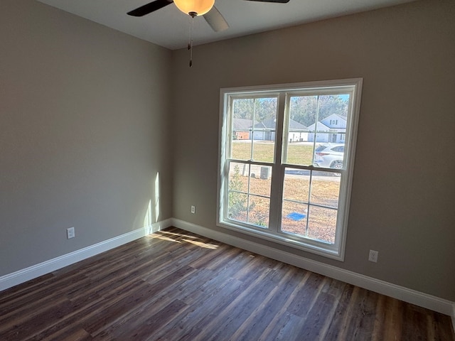 unfurnished room featuring dark wood-style floors, plenty of natural light, a ceiling fan, and baseboards