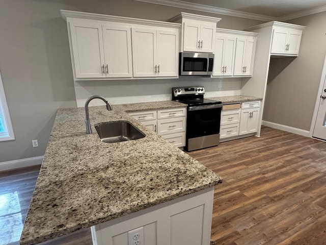 kitchen featuring white cabinets, ornamental molding, dark wood-style flooring, stainless steel appliances, and a sink