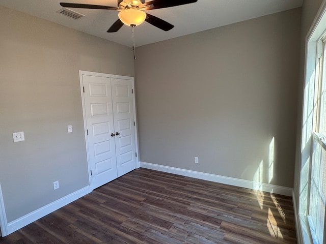 spare room with ceiling fan, dark wood-type flooring, visible vents, and baseboards