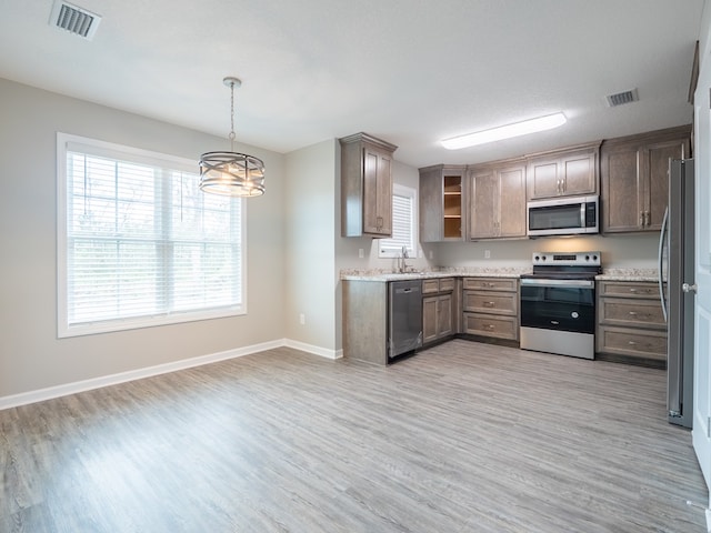 kitchen featuring appliances with stainless steel finishes, a textured ceiling, decorative light fixtures, an inviting chandelier, and light hardwood / wood-style floors