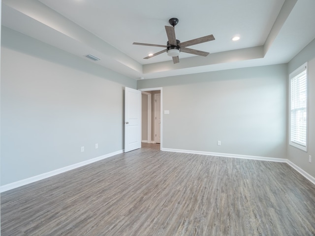 unfurnished room featuring hardwood / wood-style floors, ceiling fan, and a tray ceiling