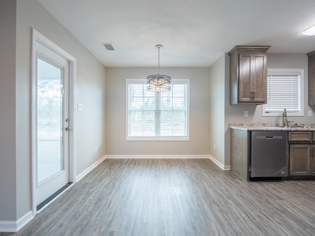 kitchen with a wealth of natural light, dishwasher, sink, light hardwood / wood-style flooring, and a chandelier