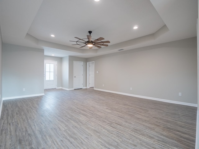 empty room with a raised ceiling and hardwood / wood-style floors