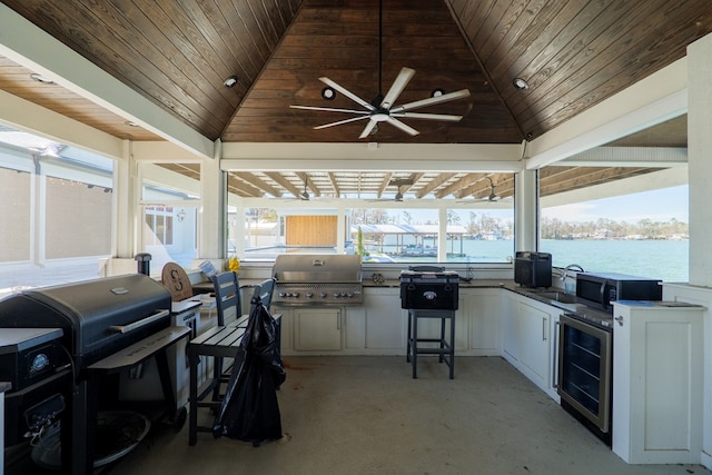 view of patio featuring a water view, beverage cooler, an outdoor kitchen, and grilling area