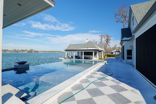 view of swimming pool featuring a water view, pool water feature, an outdoor structure, and a patio