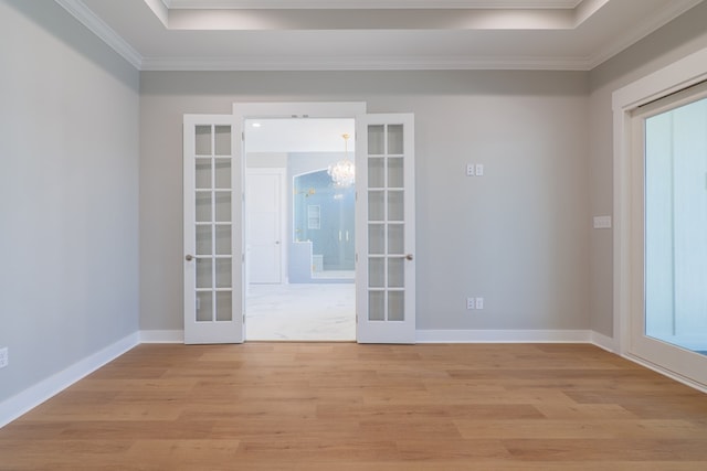 unfurnished room featuring french doors, crown molding, a chandelier, and light wood-type flooring