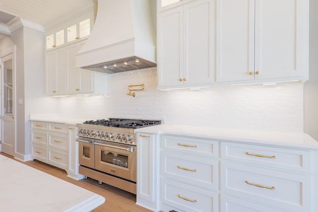 kitchen featuring white cabinetry, light stone countertops, custom range hood, and range with two ovens