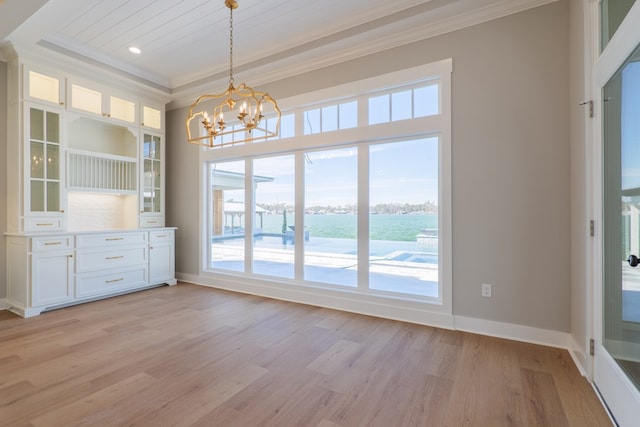 unfurnished dining area featuring crown molding, a water view, a notable chandelier, and light wood-type flooring