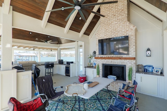 living room with high vaulted ceiling, beamed ceiling, ceiling fan, a brick fireplace, and wooden ceiling