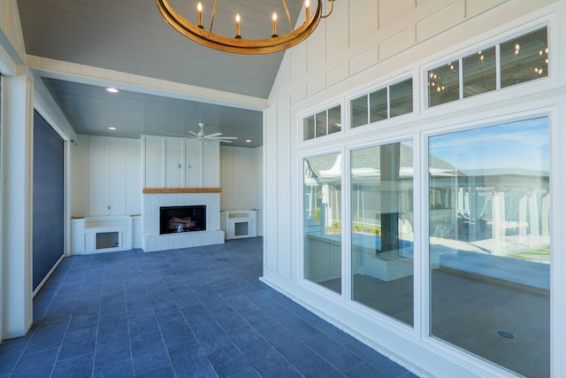 unfurnished living room with high vaulted ceiling, a fireplace, and ceiling fan with notable chandelier