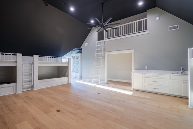 unfurnished living room with high vaulted ceiling, light hardwood / wood-style floors, sink, and ceiling fan