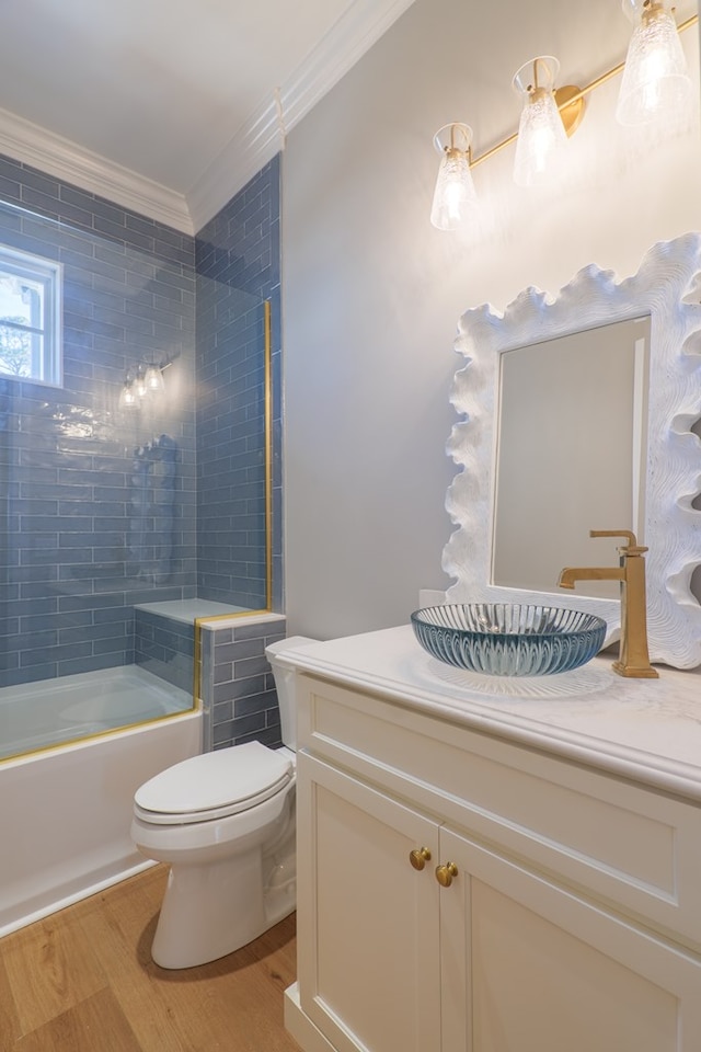 full bathroom with toilet, tiled shower / bath, ornamental molding, vanity, and hardwood / wood-style floors