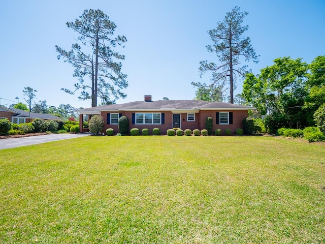 ranch-style house featuring aphalt driveway, an attached carport, and a front lawn