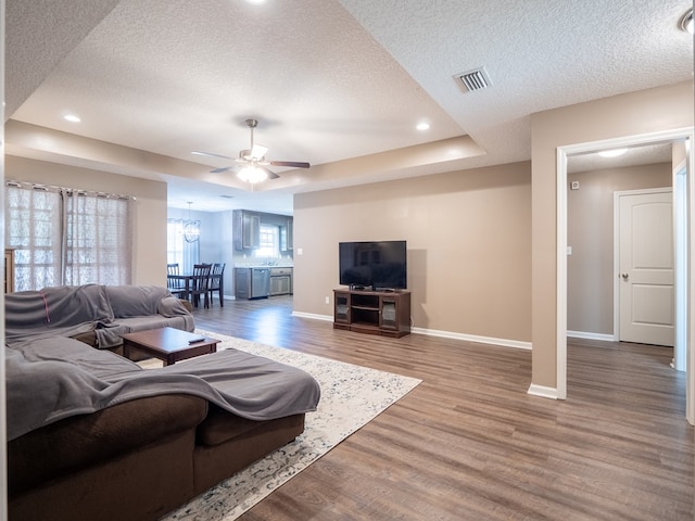 living room featuring a textured ceiling, wood finished floors, visible vents, and baseboards