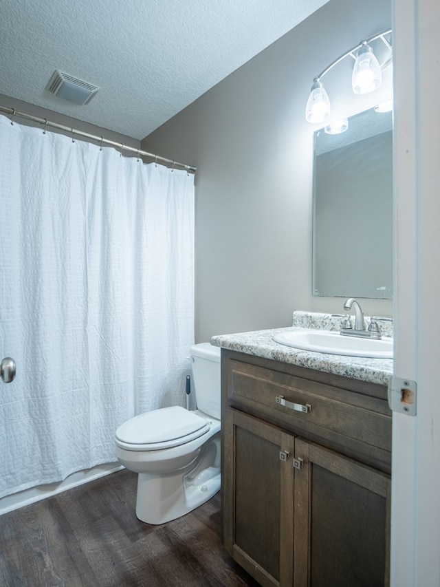 bathroom with vanity, wood finished floors, visible vents, a textured ceiling, and toilet