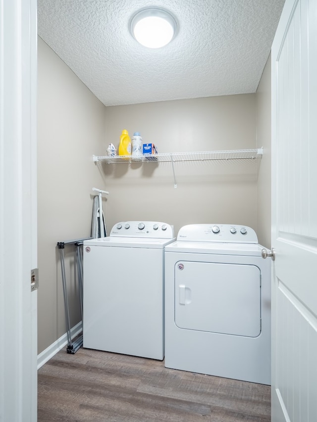 laundry area with a textured ceiling, wood finished floors, laundry area, and washer and clothes dryer