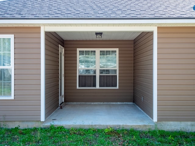 entrance to property featuring roof with shingles