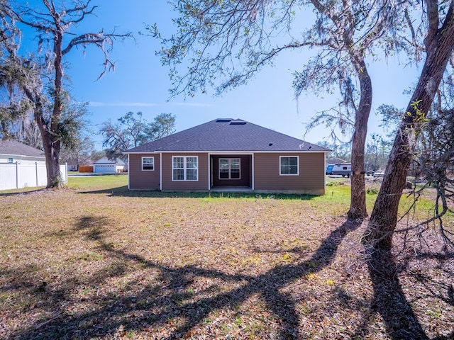 back of house featuring a lawn and fence