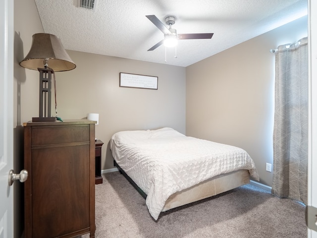 carpeted bedroom featuring baseboards, visible vents, a textured ceiling, and ceiling fan