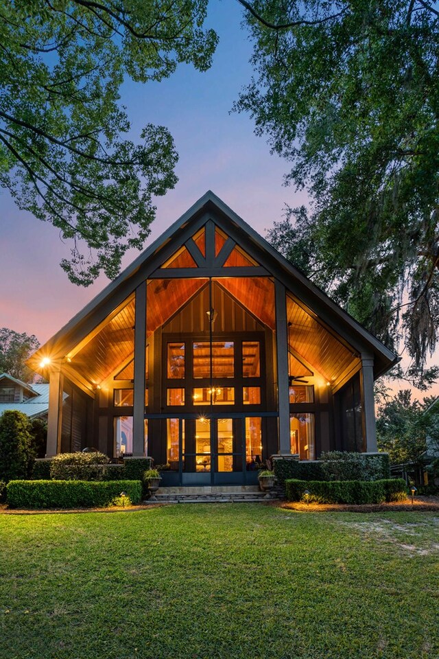 back house at dusk featuring a lawn