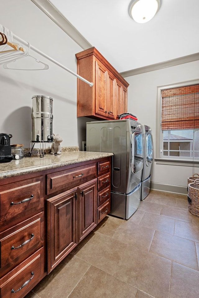 washroom with cabinets, ornamental molding, and washing machine and clothes dryer