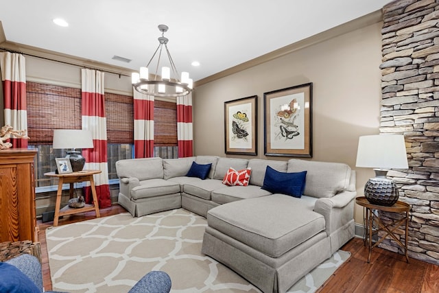 living room featuring dark wood-type flooring, crown molding, and a notable chandelier