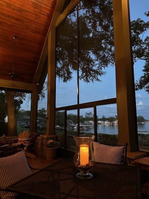 sunroom / solarium with a water view, lofted ceiling, and wooden ceiling