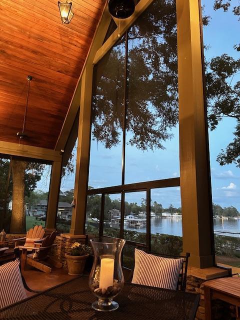 sunroom featuring a water view, lofted ceiling, and wood ceiling