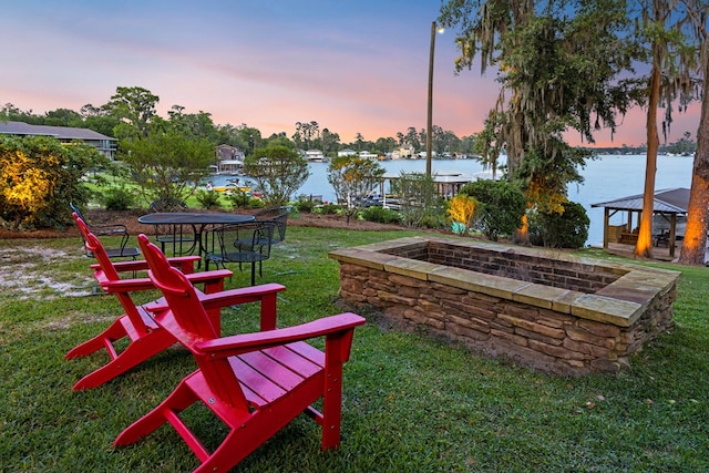 yard at dusk with a water view, an outdoor fire pit, and a gazebo