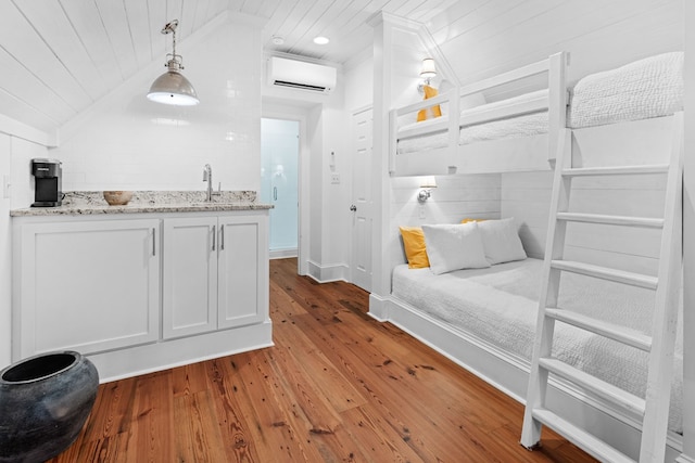 bedroom with sink, hardwood / wood-style floors, a wall unit AC, vaulted ceiling, and wooden ceiling