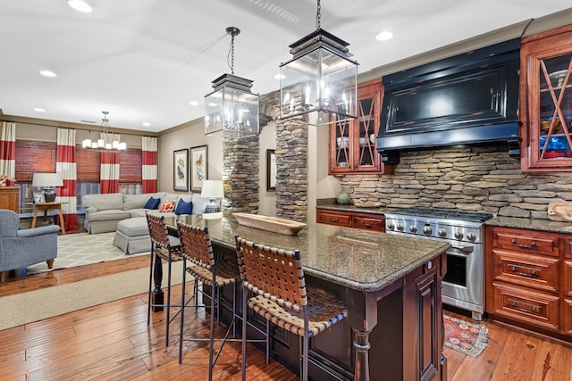 kitchen featuring high end stainless steel range oven, ornamental molding, a kitchen island, and a breakfast bar