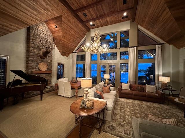 interior space with wood ceiling, beam ceiling, high vaulted ceiling, a notable chandelier, and a fireplace