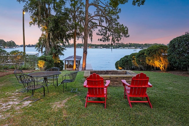 yard at dusk with a gazebo and a water view