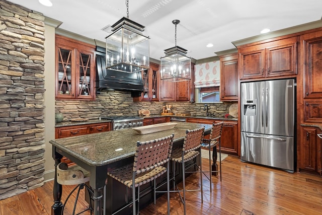 kitchen with sink, a kitchen bar, a center island, range, and stainless steel fridge with ice dispenser