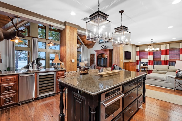 kitchen featuring appliances with stainless steel finishes, a center island, wine cooler, a kitchen bar, and vaulted ceiling