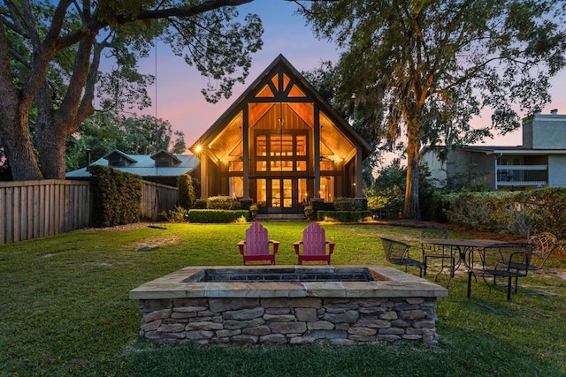 back house at dusk with a fire pit and a lawn