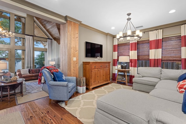 living room with ornamental molding, high vaulted ceiling, hardwood / wood-style floors, and an inviting chandelier