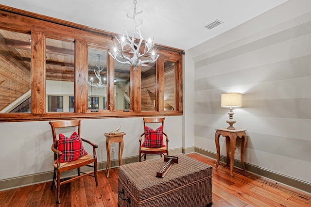 sitting room with an inviting chandelier and hardwood / wood-style floors